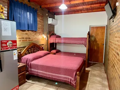 a small bedroom with two beds and a refrigerator at Departamentos La Morita in Embalse