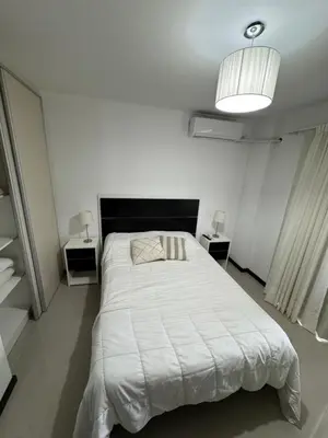 a white bedroom with a bed and two night stands at Complejo Venetto Village in Villa Parque Siquiman