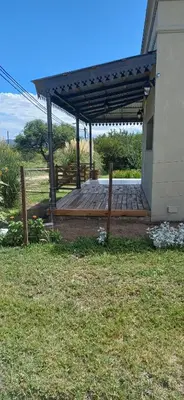 a wooden deck with awning next to a house at LA VALENTINA casa de campo in Villa Cura Brochero