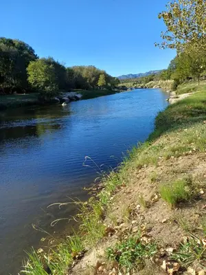 a river next to a grassy field next to a field at LA VALENTINA casa de campo in Villa Cura Brochero