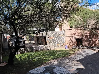 a tree in front of a building with a stone wall at Lagriega in Cuesta Blanca