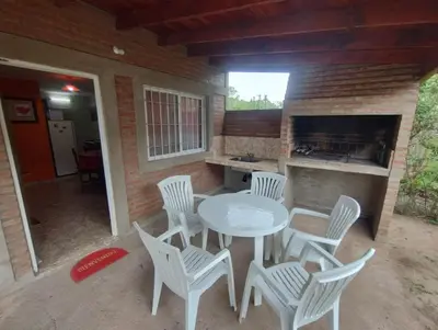 a patio with a table and chairs and a kitchen at Cabañas La Casita de Fran in Villa del Dique
