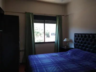 a bedroom with a blue bed and a window at Deptos Carlos Paz A in Villa Carlos Paz