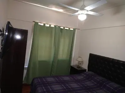 a bedroom with a green curtain and a ceiling fan at Deptos Carlos Paz A in Villa Carlos Paz