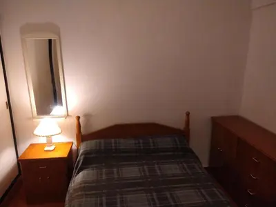 a small bedroom with a bed and a lamp at Deptos Carlos Paz B in Villa Carlos Paz