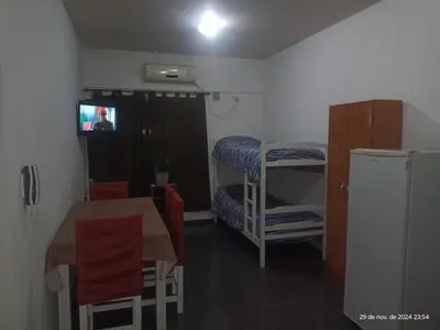 a small room with a table and a tv and a kitchen at Deptos Carlos Paz B in Villa Carlos Paz