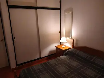 a bedroom with a bed and a lamp on a table at Deptos Carlos Paz B in Villa Carlos Paz