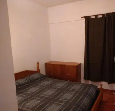 a bedroom with a bed and a dresser and a window at Deptos Carlos Paz B in Villa Carlos Paz