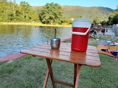 a red and white cooler sitting on a picnic table next to a lake at Mateo y Stella 2 in Bialet Massé