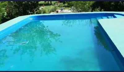 a blue swimming pool with a tree in it at Hosteria Calamuchita in Villa del Dique