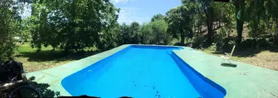 a blue swimming pool in a yard with trees at Hosteria Calamuchita in Villa del Dique