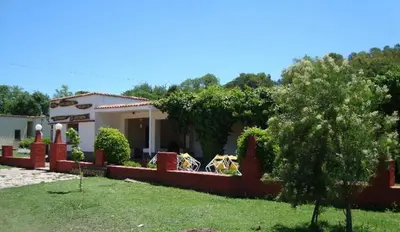 a house with a fence in front of a yard at Hosteria Calamuchita in Villa del Dique