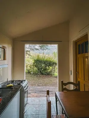 a kitchen with an open door to a yard at Cabaña La Resolana in Villa Alpina