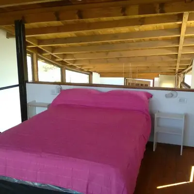 a bed with a pink blanket in a room at Cabañas Amanecer en Los Molinos in La Estancia