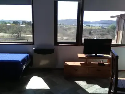 a bedroom with a bed and a desk with a television at Cabañas Amanecer en Los Molinos in La Estancia