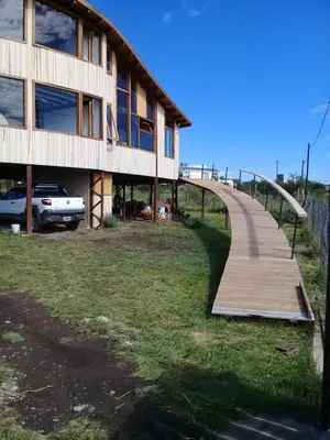 a wooden walkway leading to a building at Cabañas Amanecer en Los Molinos in La Estancia