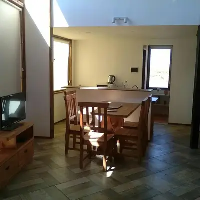 a kitchen with a table and chairs and a television at Cabañas Amanecer en Los Molinos in La Estancia