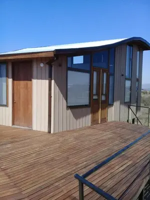 a house with a wooden deck with a building at Cabañas Amanecer en Los Molinos in La Estancia
