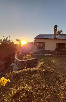 a house with the sun setting in the background at Casa en la montaña, Rincón del Este - Merlo SL in Merlo