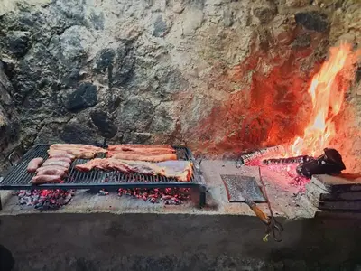 a grill with a bunch of meat and a fire at Casa en la montaña, Rincón del Este - Merlo SL in Merlo