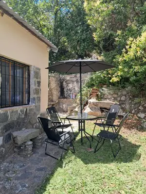 a patio with a table and chairs and an umbrella at Casa en la montaña, Rincón del Este - Merlo SL in Merlo