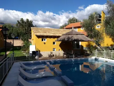 a pool with chairs and an umbrella next to a building at Cabañas Pio Pio in Merlo