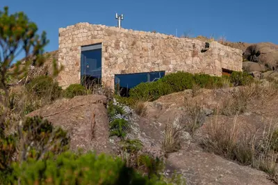 a stone house on a hill with a cross on it at Rustic Mountain Shelter Pure Nature in Las Rabonas