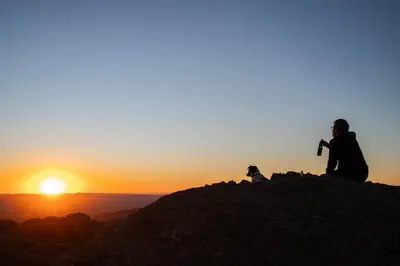 a man sitting on top of a mountain at sunset at Rustic Mountain Shelter Pure Nature in Las Rabonas