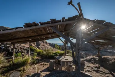a wooden shelter with a bench in the desert at Rustic Mountain Shelter Pure Nature in Las Rabonas