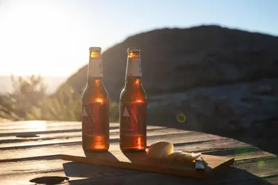 two bottles of beer sitting on a wooden table at Rustic Mountain Shelter Pure Nature in Las Rabonas