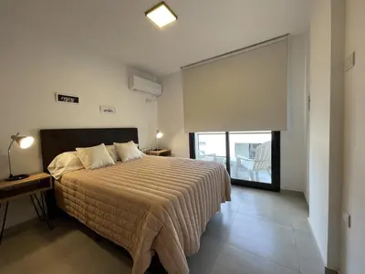 a bedroom with a bed and a large window at Depto Paseo Quattro in Villa Carlos Paz