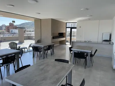 a dining room with tables and chairs and a kitchen at Depto Paseo Quattro in Villa Carlos Paz