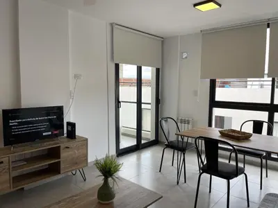 a living room with a dining room table and a television at Depto Paseo Quattro in Villa Carlos Paz