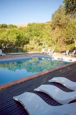 a swimming pool with two white chairs next to it at Cabañas del Bosque in Merlo