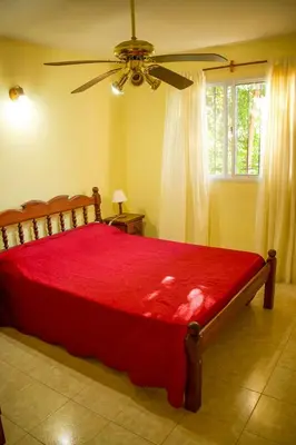 a bedroom with a red bed with a ceiling fan at Cabañas del Bosque in Merlo