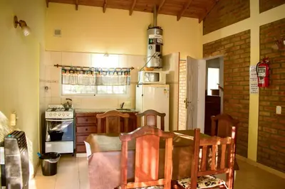 a kitchen with a table and a white refrigerator at Cabañas del Bosque in Merlo