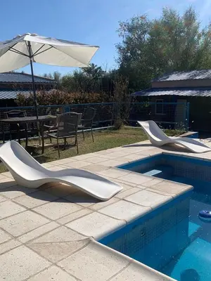 a swimming pool with two white chairs and an umbrella at Don Valerio in Mina Clavero