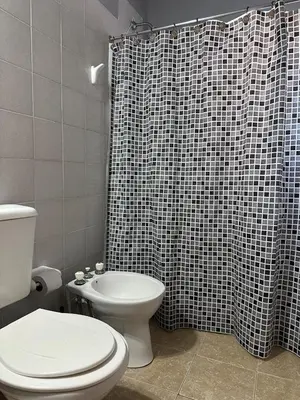 a bathroom with a toilet and a black and white shower curtain at Don Valerio in Mina Clavero