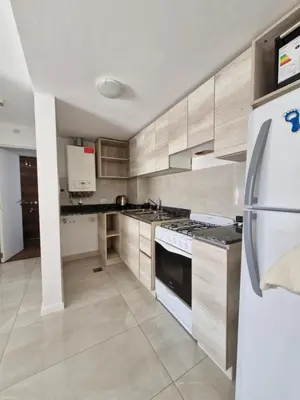 a kitchen with wooden cabinets and a white refrigerator at Bonito departamento in Cordoba