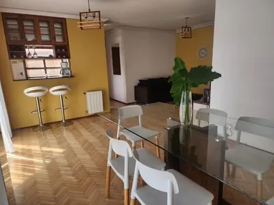 a dining room with a glass table and white chairs at FANTASTICO departamento en el CENTRO DE CARLOS PAZ in Villa Carlos Paz