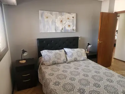 a bedroom with a bed with a flower painting on the wall at FANTASTICO departamento en el CENTRO DE CARLOS PAZ in Villa Carlos Paz