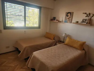 a room with two beds and a window with blinds at FANTASTICO departamento en el CENTRO DE CARLOS PAZ in Villa Carlos Paz