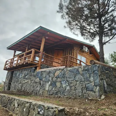 a log cabin on top of a stone wall at Cabaña La Lechuza in Villa Ciudad de America