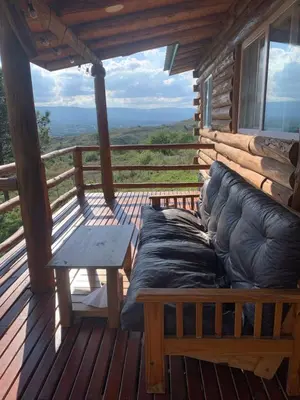 a couch sitting on a porch of a cabin at Cabaña La Lechuza in Villa Ciudad de America