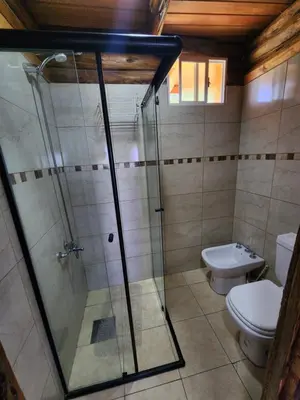 a bathroom with a glass shower and a toilet at Cabaña La Lechuza in Villa Ciudad de America