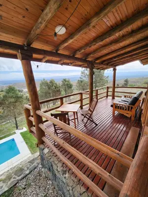 a wooden deck with a table and chairs and a pool at Cabaña La Lechuza in Villa Ciudad de America