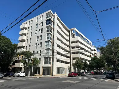 a tall white building on a city street with cars at Depto Balcones Cofico 4 in Cordoba