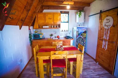 a kitchen with a wooden table with chairs and a refrigerator at Cabaña Yael in Villa Parque Siquiman