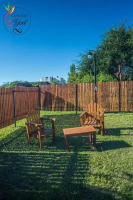 three wooden benches sitting in the grass near a fence at Cabaña Yael in Villa Parque Siquiman