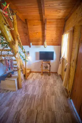 a living room with a television and wooden ceilings at Cabaña Yael in Villa Parque Siquiman
